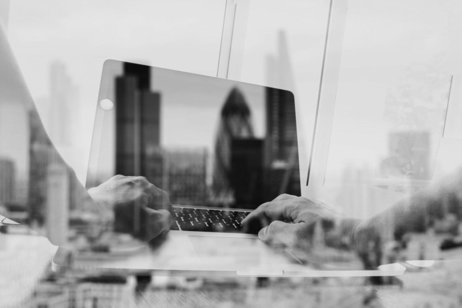 Close-up of hands typing code on laptop with blockchain network visualization on screen showing connected nodes and transaction flows